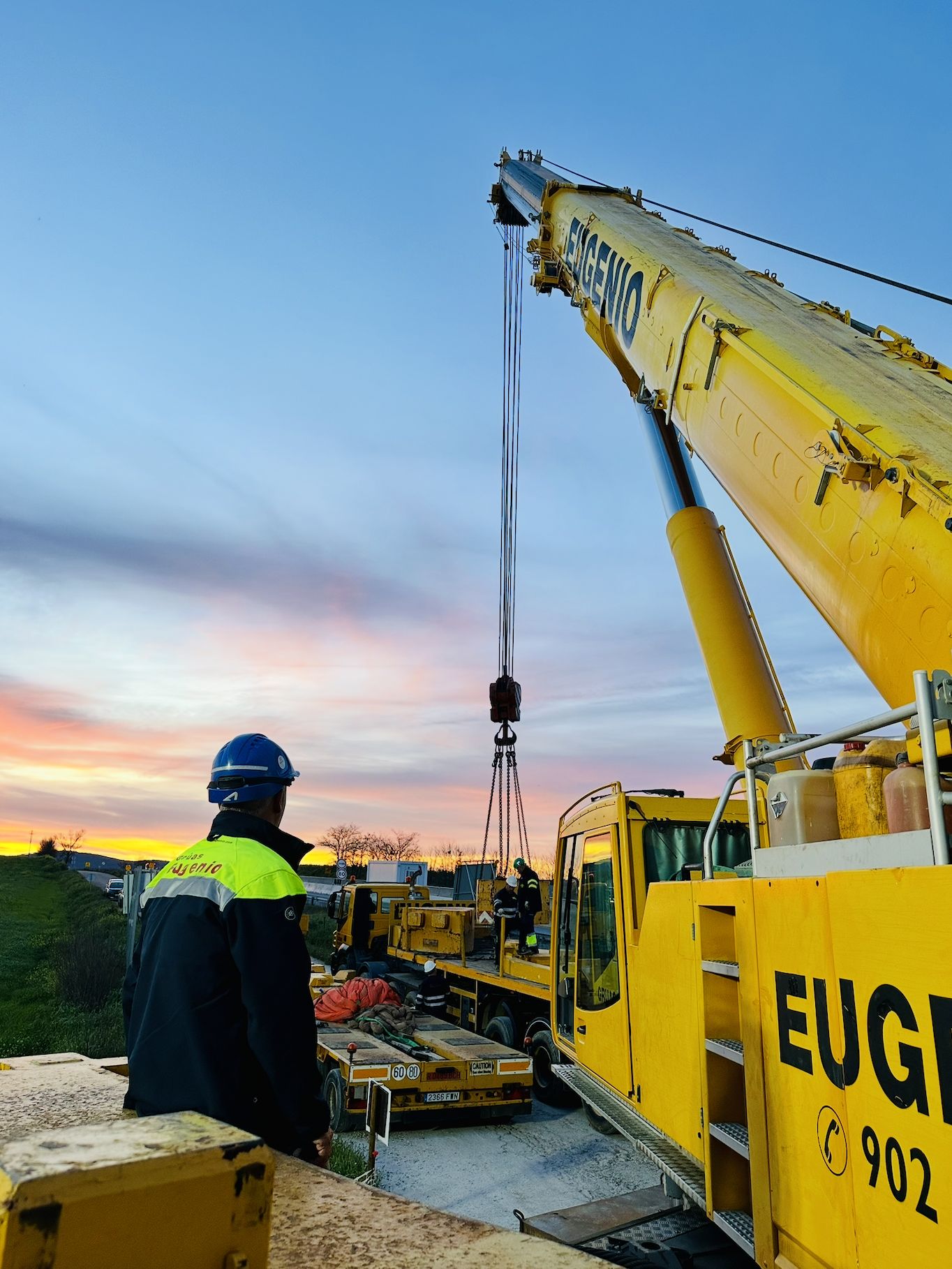 Equipo cargando maquinaria en una góndola al atardecer